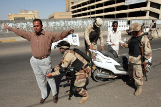 جنود عراقيون يفتشون مواطنا في احدى نقاط التفتيش في بغداد