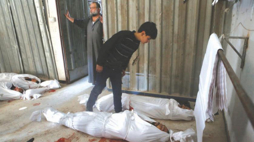 فتى يتحقق من هوية أحد القتلى بعد غارة على غوطة دمشق 