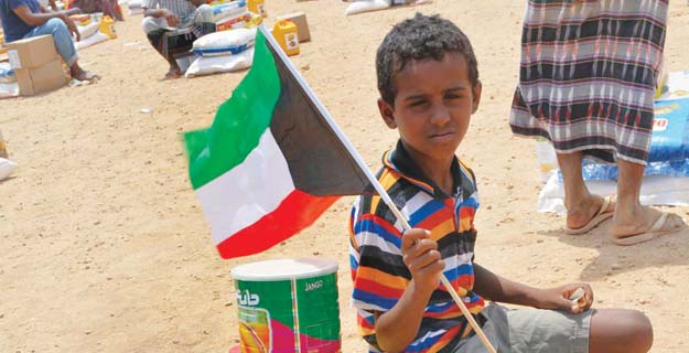 طفل يمني يرفع علم الكويت بعد توزيع المساعدات (النجاة الخيرية)