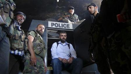 مقاتلون في صفوف الجيش السوري الحر في صورة أمام مدرعة للشرطة يقول