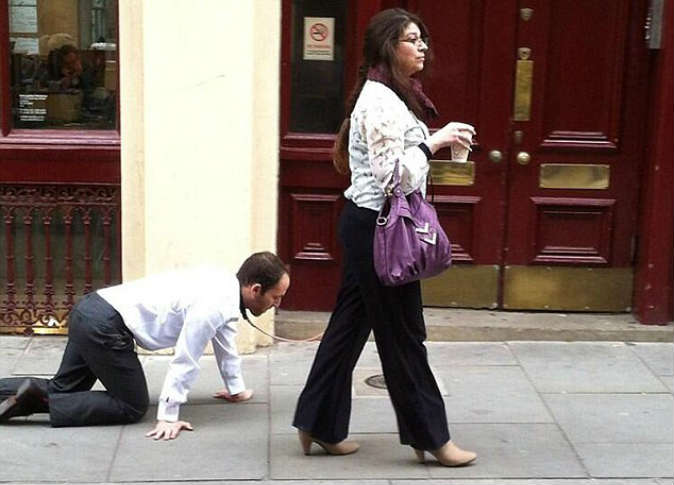 بالصور.. امرأة تتجول في شوارع لندن وتسحب رجلا بسلسلة