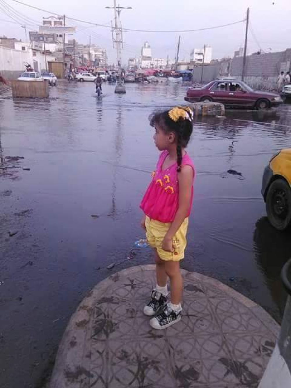 طفلة تقف وسط تقاطع في مدينة عدن سدته مياه المجاي