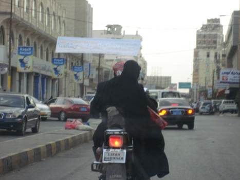 امرأة تركب الدراجة إلى جوار شخص اخر بشارع الزبيري وسط العاصمة صن